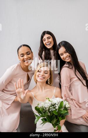 photographie de mariage, diversité culturelle, quatre femmes, mariée avec ses demoiselles multiculturelles regardant l'anneau d'engagement, brune et blonde, positiv Banque D'Images