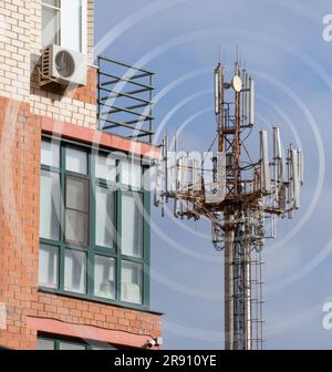 Antenne de télécommunication sur une tour près d'un immeuble résidentiel de plusieurs étages. Antenne de téléphone cellulaire en zone urbaine. Banque D'Images