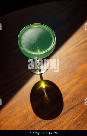 absinthe verte dans un verre coupé avec sur une table en bois au soleil avec ombre Banque D'Images