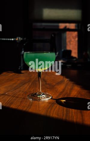 absinthe verte dans un verre coupé avec sur une table en bois au soleil avec ombre Banque D'Images