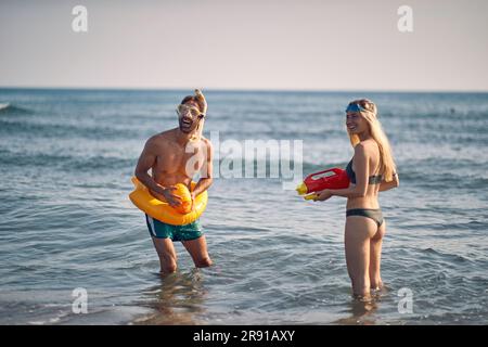 Couple d'amis ayant un pistolet à eau se battent sur la plage Banque D'Images