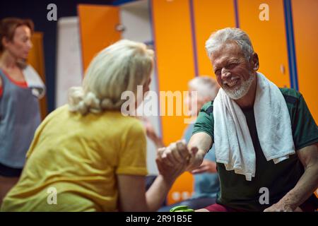 Charmant couple senior et femme dans le dressing de salle de gym en train de se serrer les uns les autres après la séance d'entraînement. Concept santé et bien-être. Banque D'Images