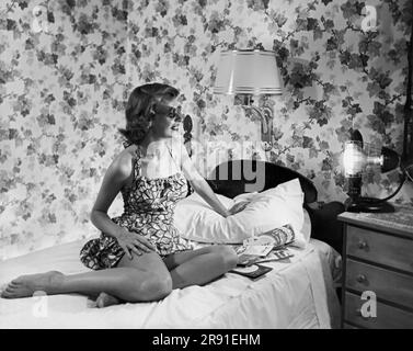 Cleveland, Ohio: Juin, 1951 Une jeune femme dans un maillot de bain utilisant une lampe de soleil dans sa chambre pour obtenir un bronzage. Banque D'Images