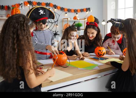 Jeune enseignante avec ses petits élèves en classe se préparant pour Halloween. Banque D'Images