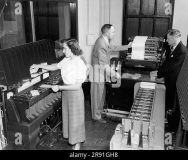 Cleveland, Ohio : février 1951 Une femme qui charge des cartes perforées et deux hommes qui consultent un imprimé d'une machine comptable IBM aux bureaux de Erie Railroad. Banque D'Images