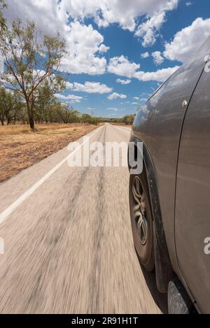 Une voiture qui longe une longue route dans l'Outback australien Banque D'Images