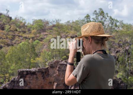 Une femme dans un chapeau de soleil regarde la vue à travers une paire de jumelles près de Jabiru dans le parc national de Kakadu en Australie Banque D'Images