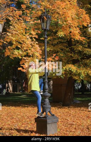 La photo a été prise dans la ville d'Odessa. Dans l'image, une jeune femme gaie essaie de monter un lampadaire de rue. Banque D'Images