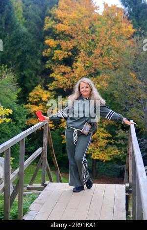 La photo a été prise en Ukraine. La photo montre une jeune femme dans un survêtement avec un téléphone rouge sur le fond de la forêt carpatique d'automne. Banque D'Images