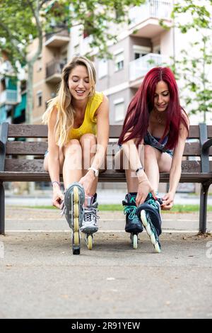 Des amis souriants portant des patins en ligne assis sur un banc Banque D'Images