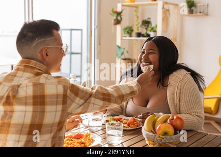 Homme essuyant le visage d'une femme à la table à manger Banque D'Images