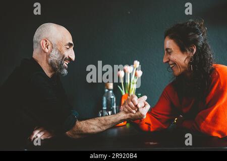 Bonne femme bras lutte avec l'homme devant le mur noir Banque D'Images