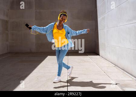 Femme insouciante dansant et écoutant de la musique par temps ensoleillé Banque D'Images