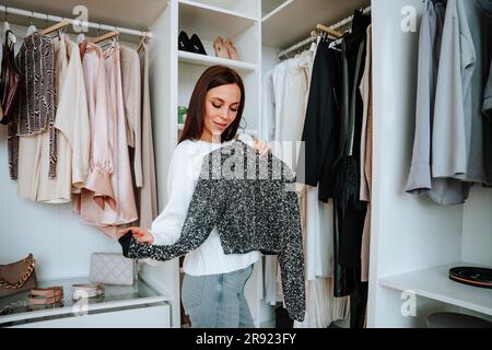 Femme regardant le dessus noir près de l'armoire dans le placard Banque D'Images