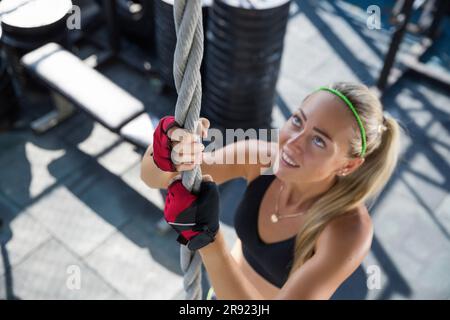 Femme souriante, corde d'escalade à la salle de gym située sur le toit Banque D'Images