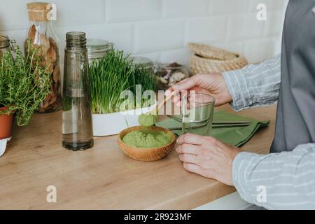 Femme préparant du jus de wheatgrass dans la cuisine à la maison Banque D'Images