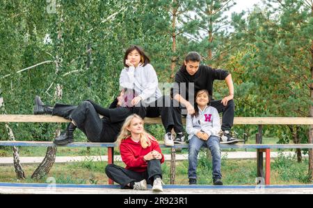 Amis multiraciaux assis sur le banc au parc Banque D'Images