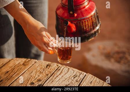 Mains de la femme versant le thé dans la tasse Banque D'Images