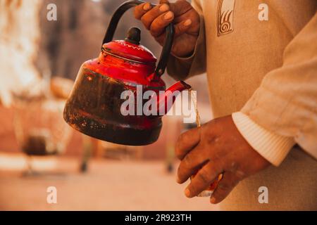 Homme avec théière versant du thé dans une tasse Banque D'Images