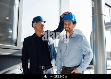 Des ingénieurs heureux portant des casques de sécurité dans l'industrie Banque D'Images