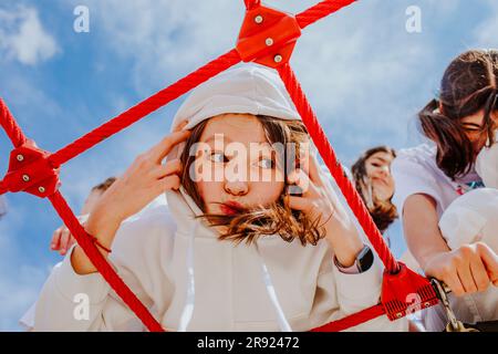 Une adolescente portant une capuche jouant à la jungle Gym sur l'aire de jeux Banque D'Images