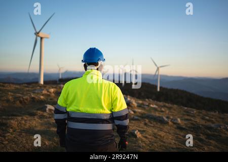 Ingénieur portant un costume réfléchissant regardant les éoliennes Banque D'Images