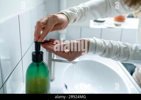 Femme mature se lavant les mains dans la salle de bains à la maison Banque D'Images