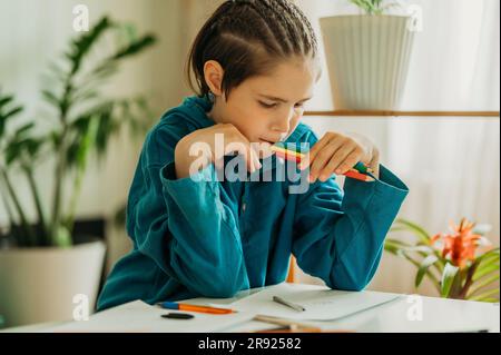 Garçon attentionné tenant des crayons de couleur à la maison Banque D'Images