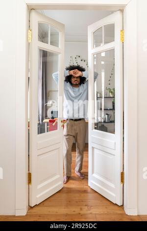 Jeune homme s'appuyant sur les portes à la maison Banque D'Images