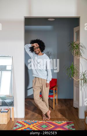 Homme souriant s'inclinant sur le mur à la maison Banque D'Images