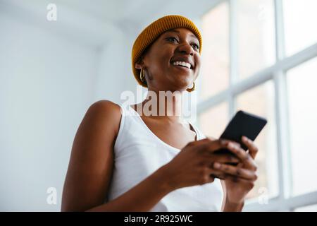 Bonne femme d'affaires vêtue d'un chapeau tricoté tenant un smartphone Banque D'Images