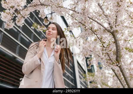 Jeune femme d'affaires debout sous l'arbre de fleur de cerisier Banque D'Images