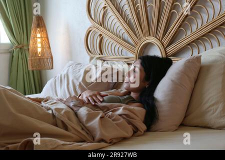 Young woman lying on bed at home Banque D'Images