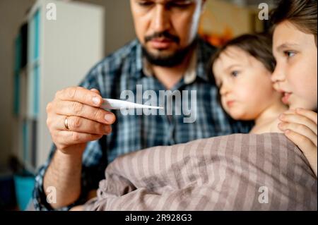 Père examinant la température du fils malade Banque D'Images