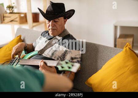 Musicien mature portant un chapeau de cow-boy jouant de la guitare électrique à la maison Banque D'Images