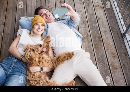 Une jeune femme heureuse avec un homme qui prend son selfie par le biais d'un smartphone Banque D'Images