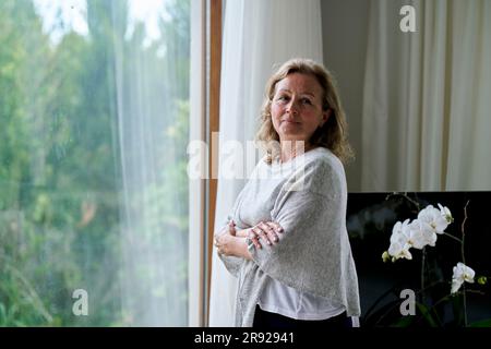 Femme sénior réfléchie debout avec les bras croisés par la fenêtre à la maison Banque D'Images