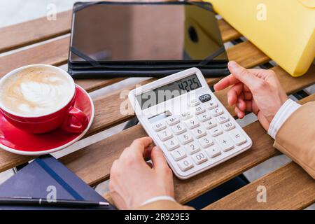 Main de femme d'affaires utilisant la calculatrice avec le café sur la table Banque D'Images