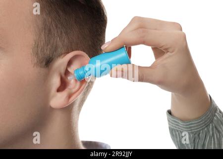 Femme qui goutte des médicaments dans l'oreille de l'homme sur fond blanc, gros plan Banque D'Images