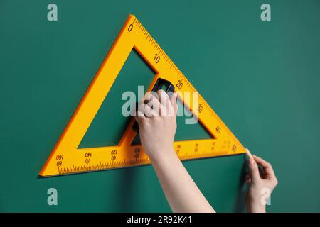 Femme dessin avec la craie et la règle de triangle sur le tableau vert, gros plan Banque D'Images