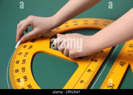 Femme dessin avec craie, règle triangulaire et rapporteur sur tableau vert, gros plan Banque D'Images