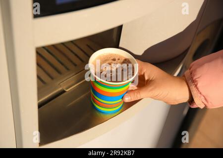 Femme prenant une tasse en papier avec du café du distributeur automatique, gros plan Banque D'Images