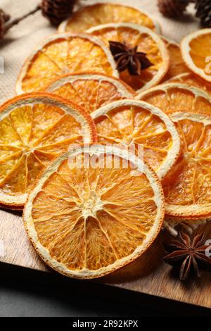 Beaucoup de tranches d'orange sèches et d'épices sur table noire, gros plan Banque D'Images
