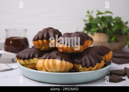 Délicieux profiteroles au chocolat sur table blanche, gros plan Banque D'Images