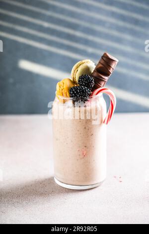 Milk-Shake extrême au chocolat avec macarons, baies et bonbons. Tendance à la fréakshake. Copier l'espace Banque D'Images