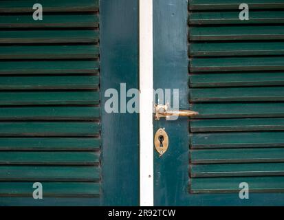 Une ancienne poignée de porte en métal sur une porte javanaise en bois vert vintage Banque D'Images