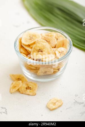 En-cas de croustilles de banane séchées dans une assiette en verre sur un tableau lumineux. Banque D'Images