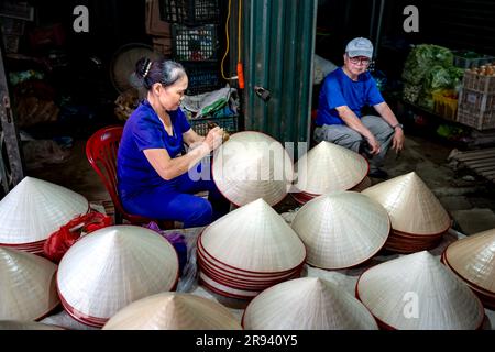 Une femme vend des chapeaux coniques faits main dans un marché de la province de Phu Tho, au Vietnam Banque D'Images