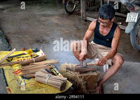 Un homme s'assoit pour fabriquer des baguettes de bambou à vendre sur un marché dans la province de Phu Tho, au Vietnam Banque D'Images