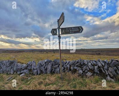 Un panneau en face d'une clôture en pierre dans le parc national de Burren. Clare, Irlande. Banque D'Images